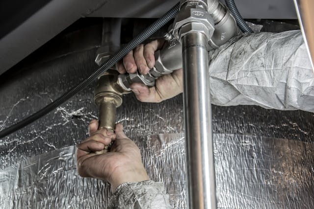 a plumber fixing pipes under a sink