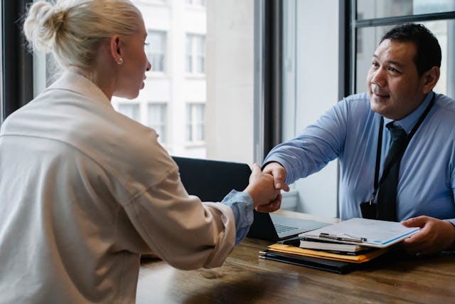 two people having a business meeting shaking hands over a desk